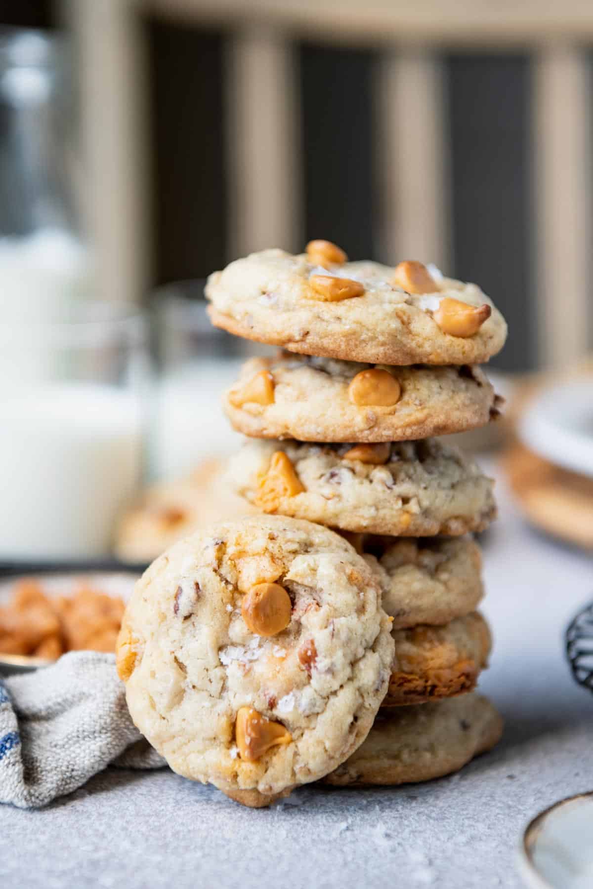 Side shot of a stack of butterscotch cookies with pecans on a white table.