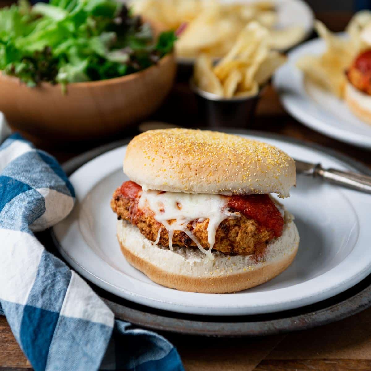 Square shot of a dinner table with a chicken parmesan sandwich with frozen chicken patties.