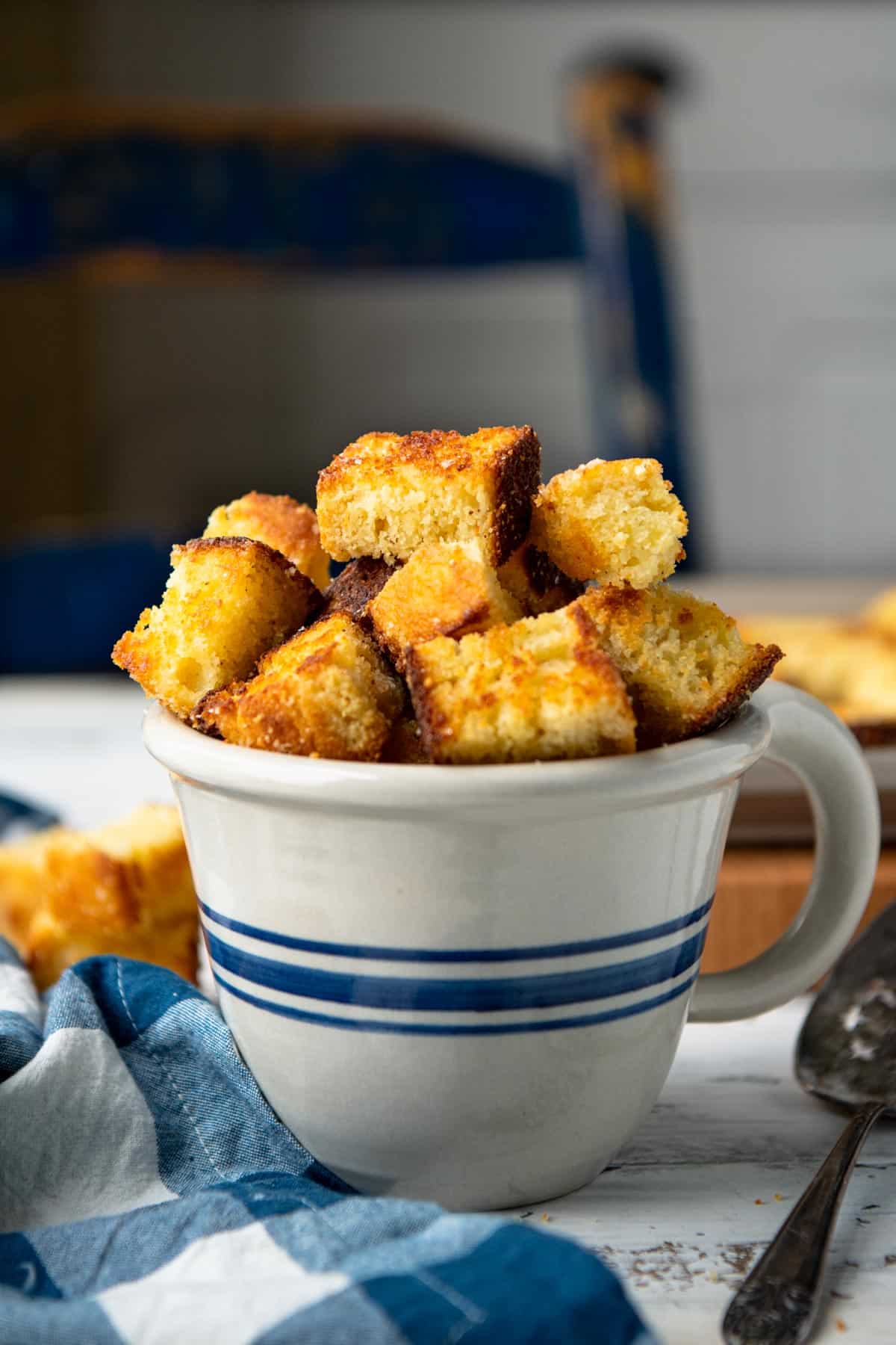 Close up side shot of a homemade cornbread croutons recipe served in a blue and white bowl.
