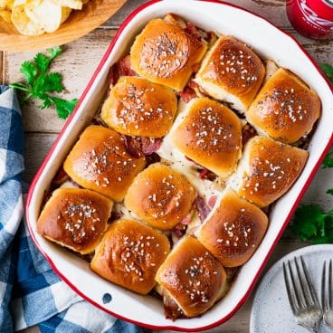 Square overhead image of crack chicken sliders in a red and white baking dish.
