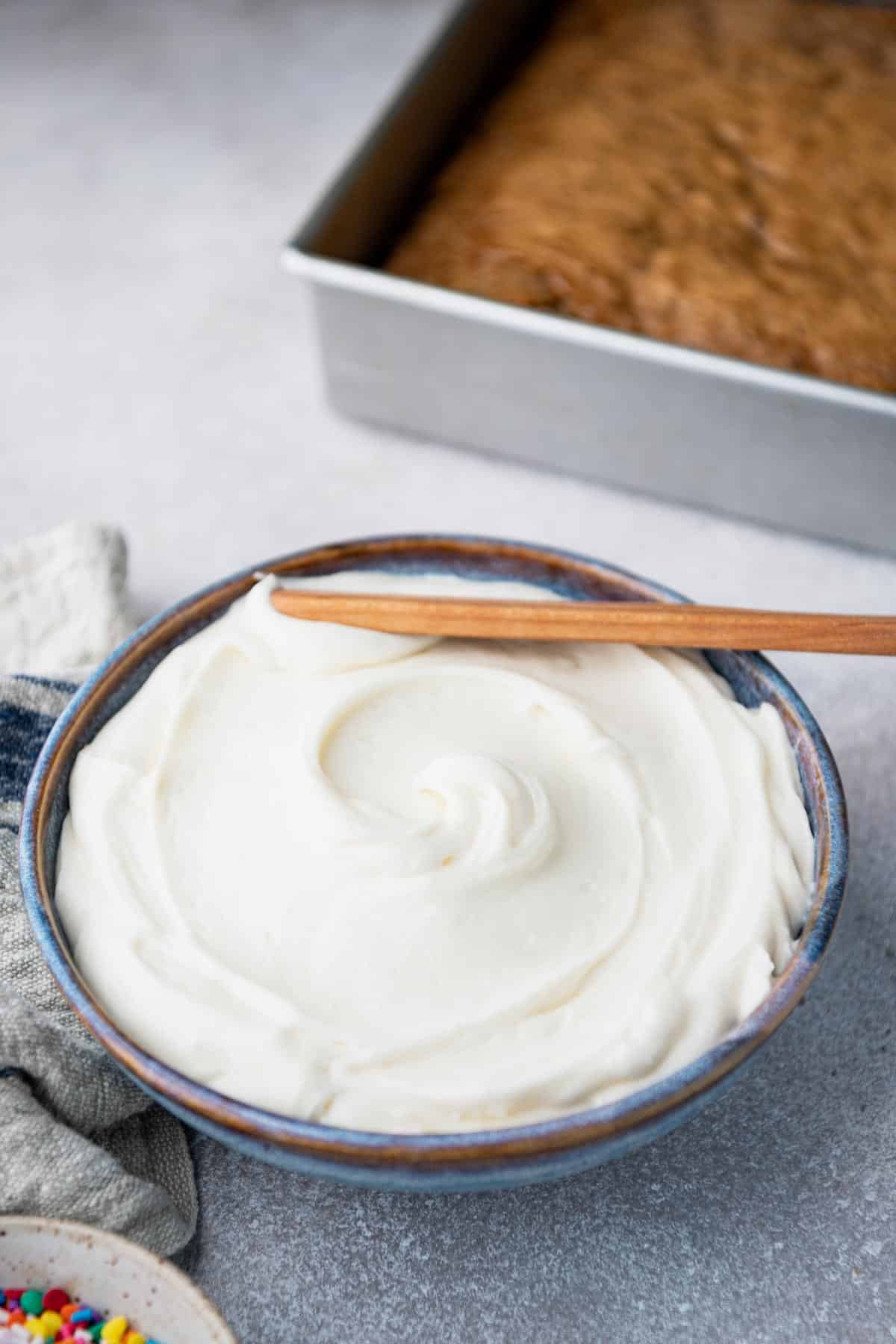 Wooden spreader in a bowl of cream cheese frosting recipe easy.