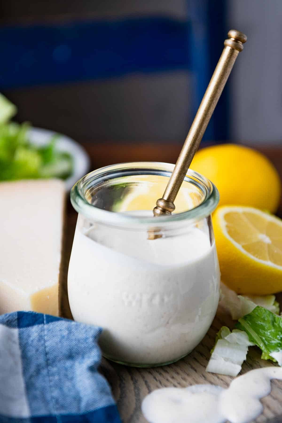 Gold spoon in a glass jar of homemade caesar salad dressing.