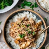 Overhead image of a fork in a bowl of crock pot maple soy chicken over rice.