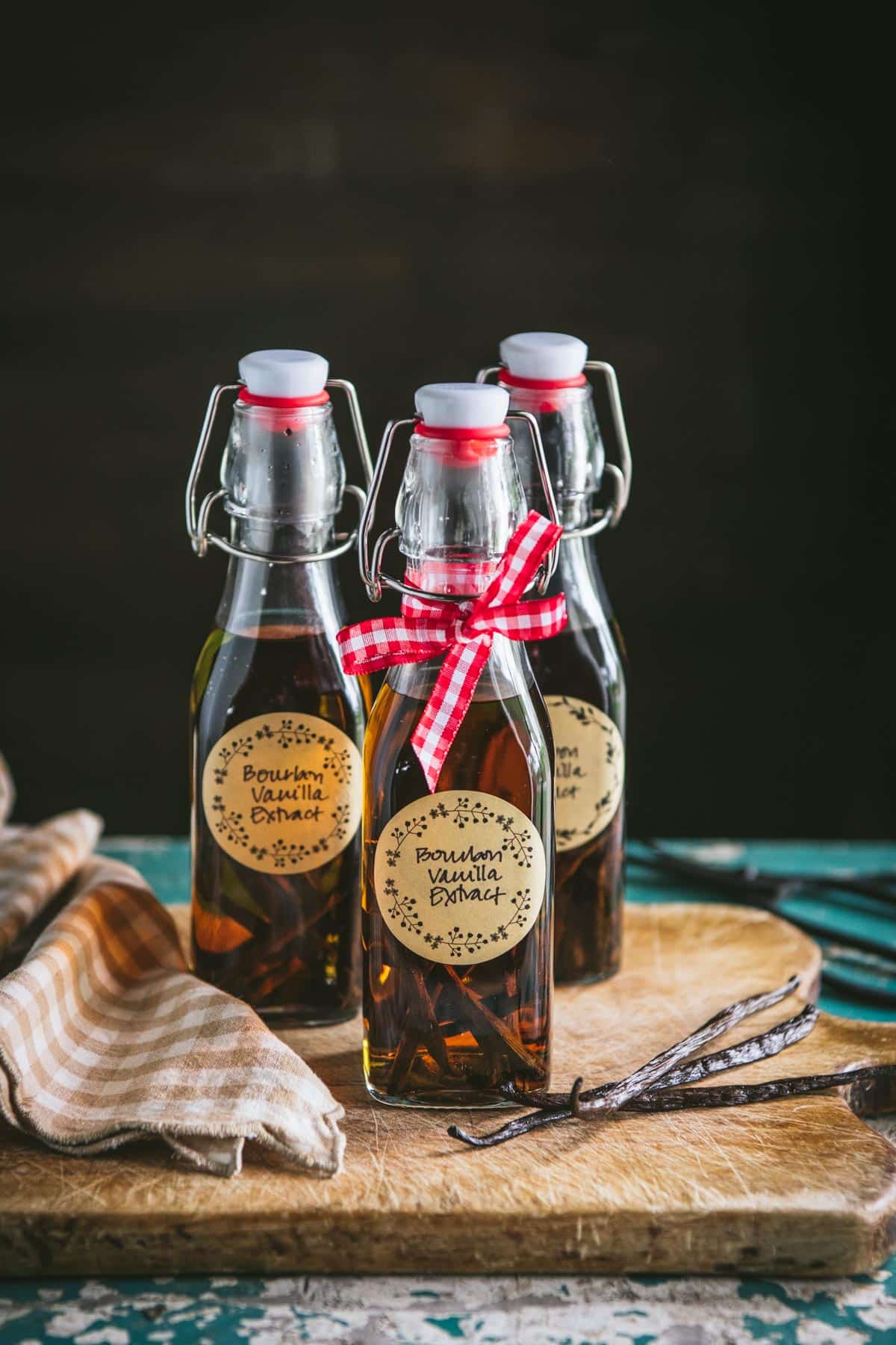 Photos showing how to make vanilla extract on a wooden cutting board.