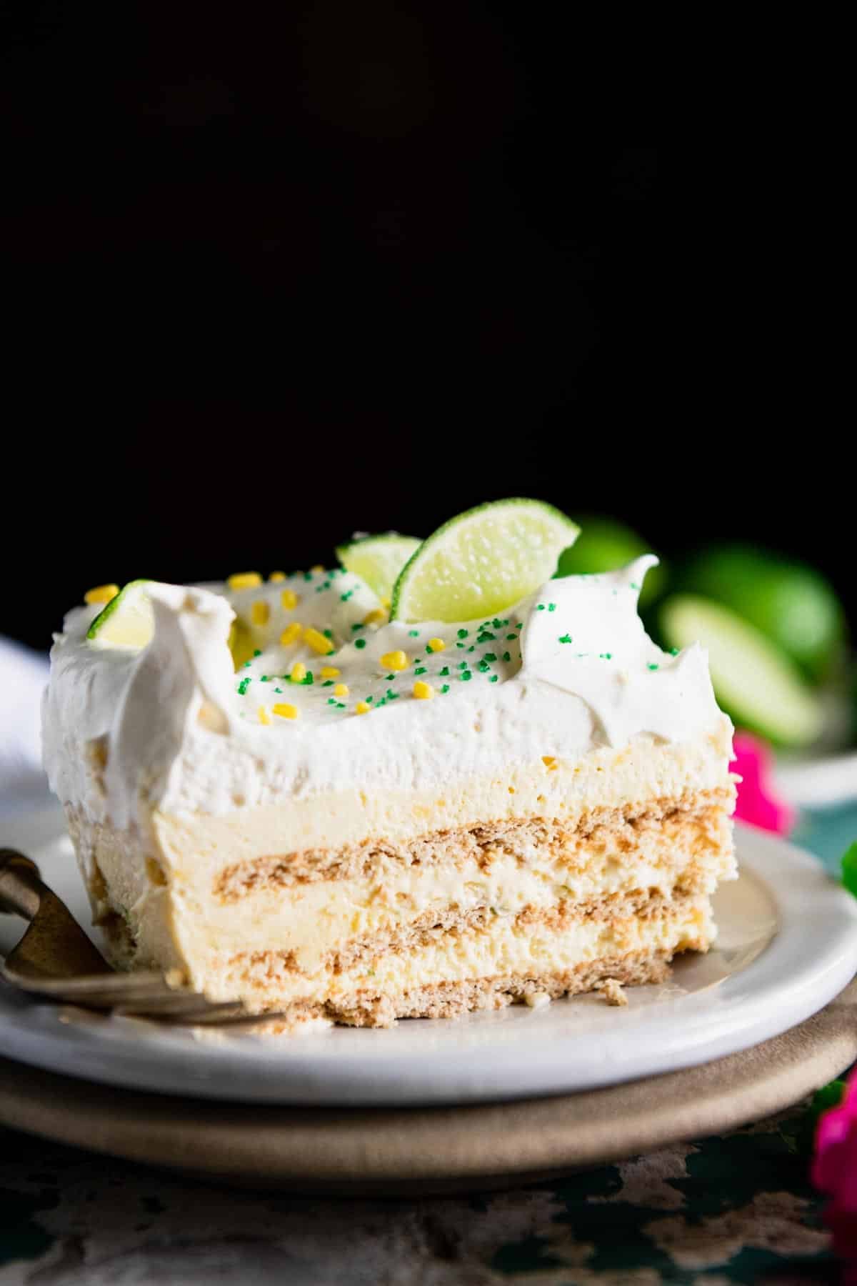 Close up side shot of a slice of key lime icebox cake in front of a black background.