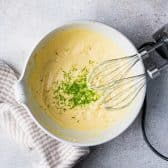Mixing key lime pudding with an electric mixer in a white mixing bowl.