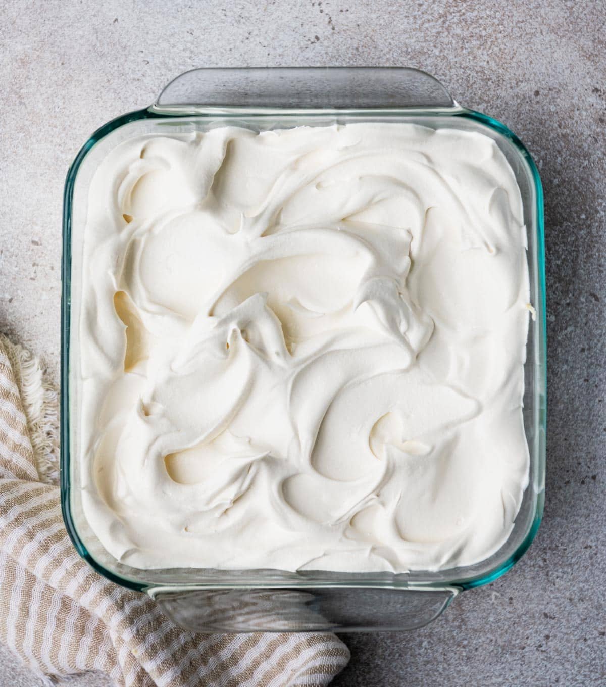 Adding cool whip to the top of a key lime icebox cake.