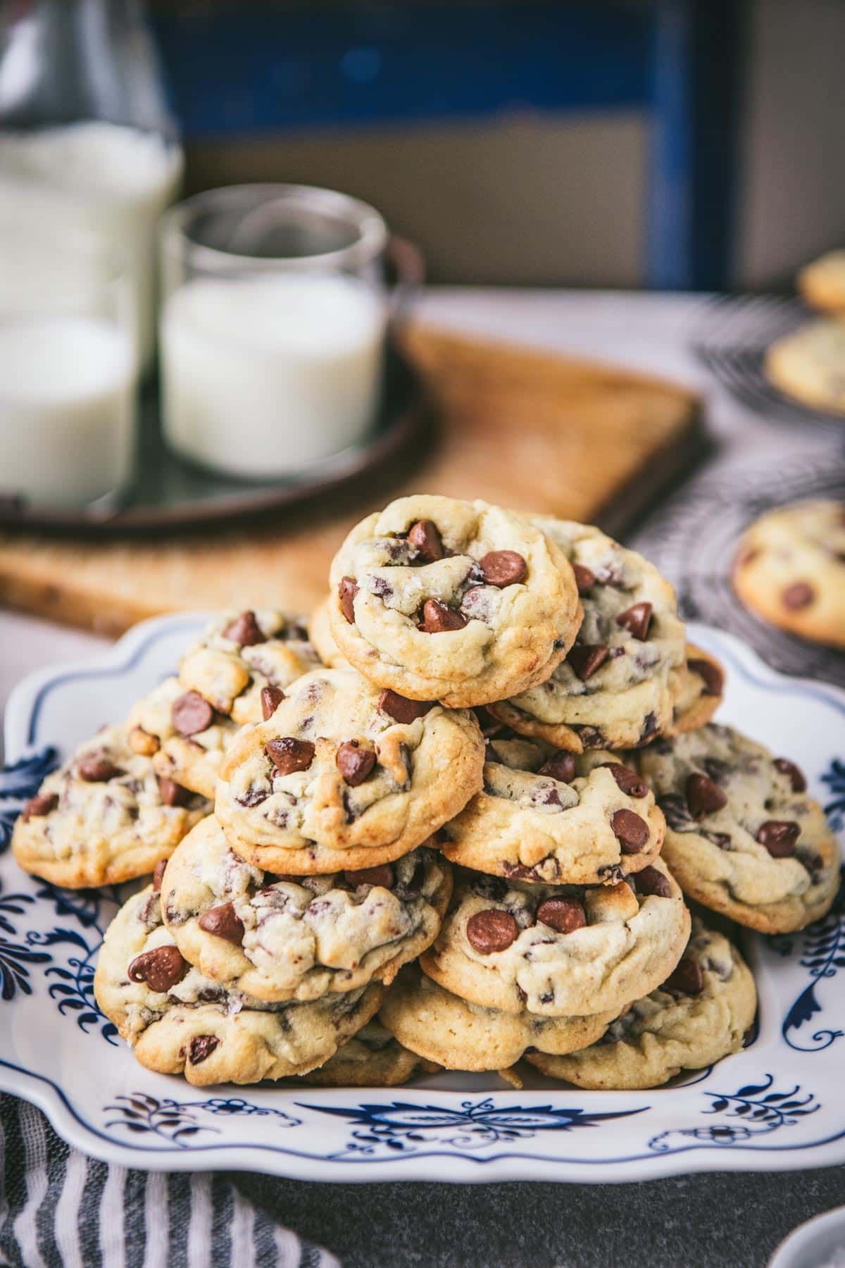 Side shot of a tray of salted chocolate chip cookies on a wooden table with milk in the background.