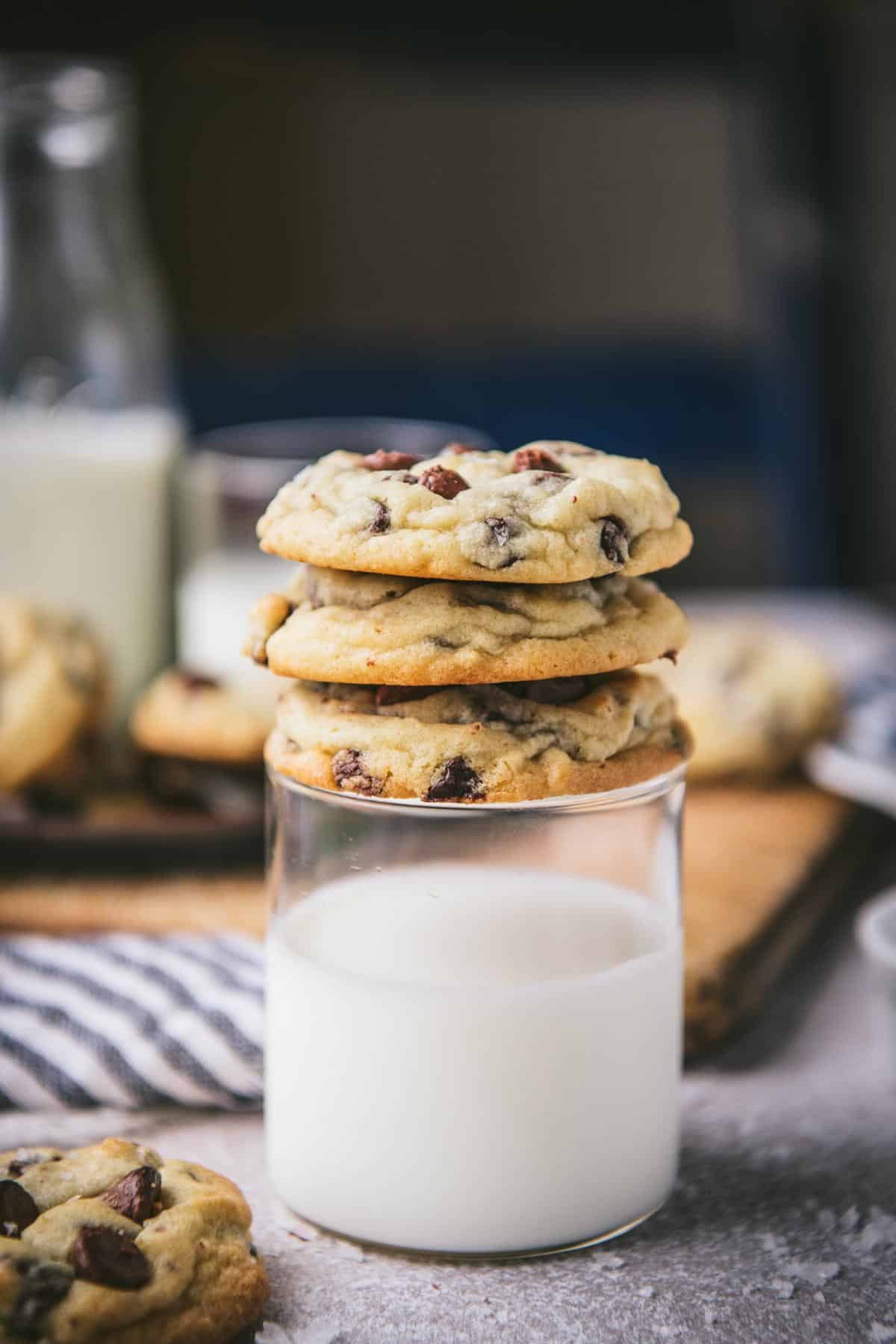 Three salted chocolate chip cookies stacked on a glass of milk.