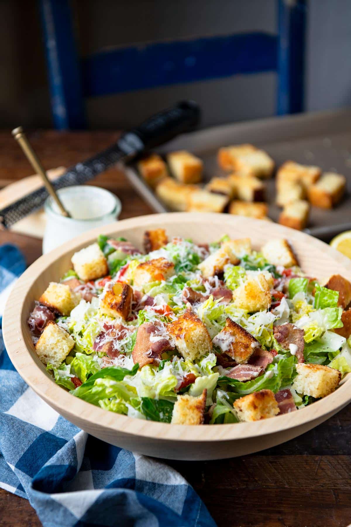 Side shot of a homemade creamy Caesar salad with cornbread croutons on a wooden table.