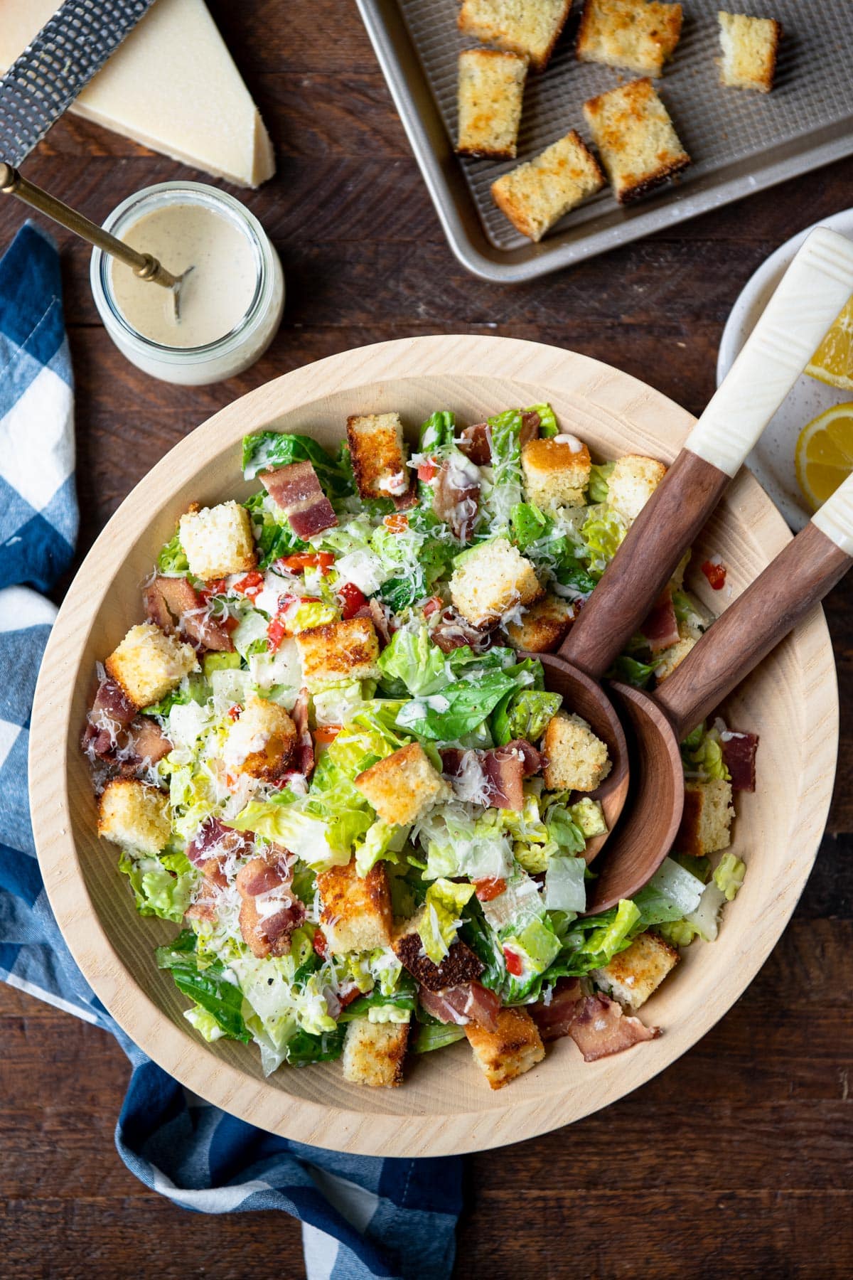 Southern Caesar salad recipe on a wooden table with creamy Caesar dressing, cornbread croutons, and crispy bacon.