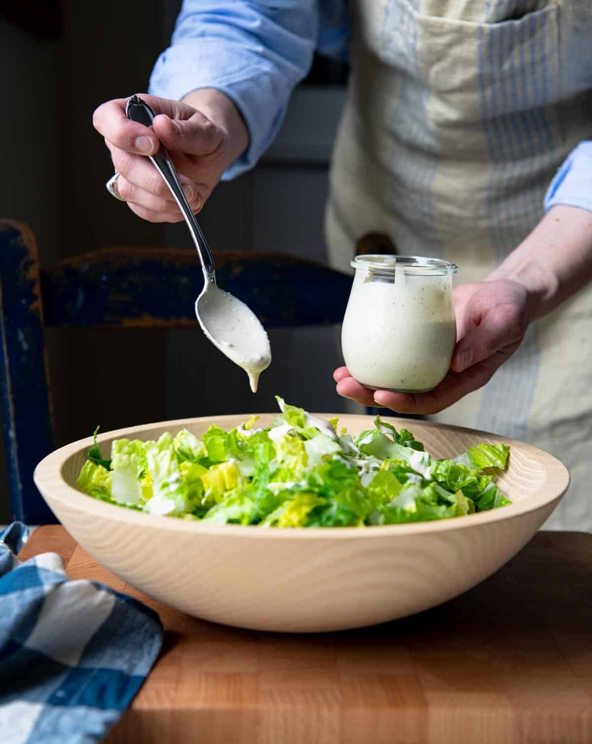 Add homemade creamy Caesar dressing to a bowl of chopped romaine lettuce.