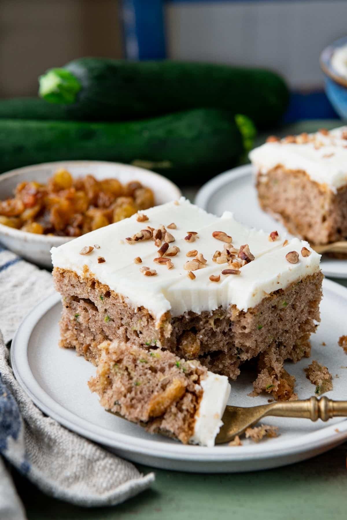 Close up side shot of an easy zucchini cake recipe on a white plate with chopped nuts on top.