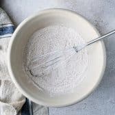 Whisking dry ingredients in a large mixing bowl.
