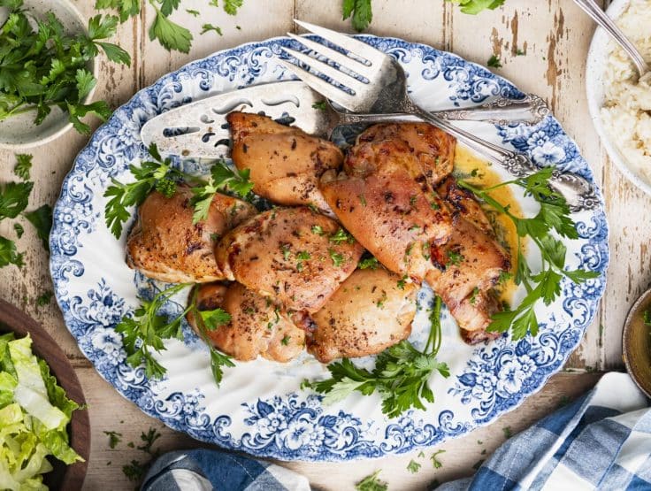 Horizontal overhead shot of a blue and white tray with bourbon marinated baked boneless skinless chicken thighs.