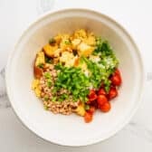 Adding veggies to the bowl with the cornbread.