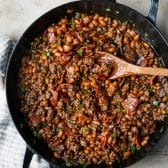 Bbq ground beef filling with baked beans in a cast iron skillet.