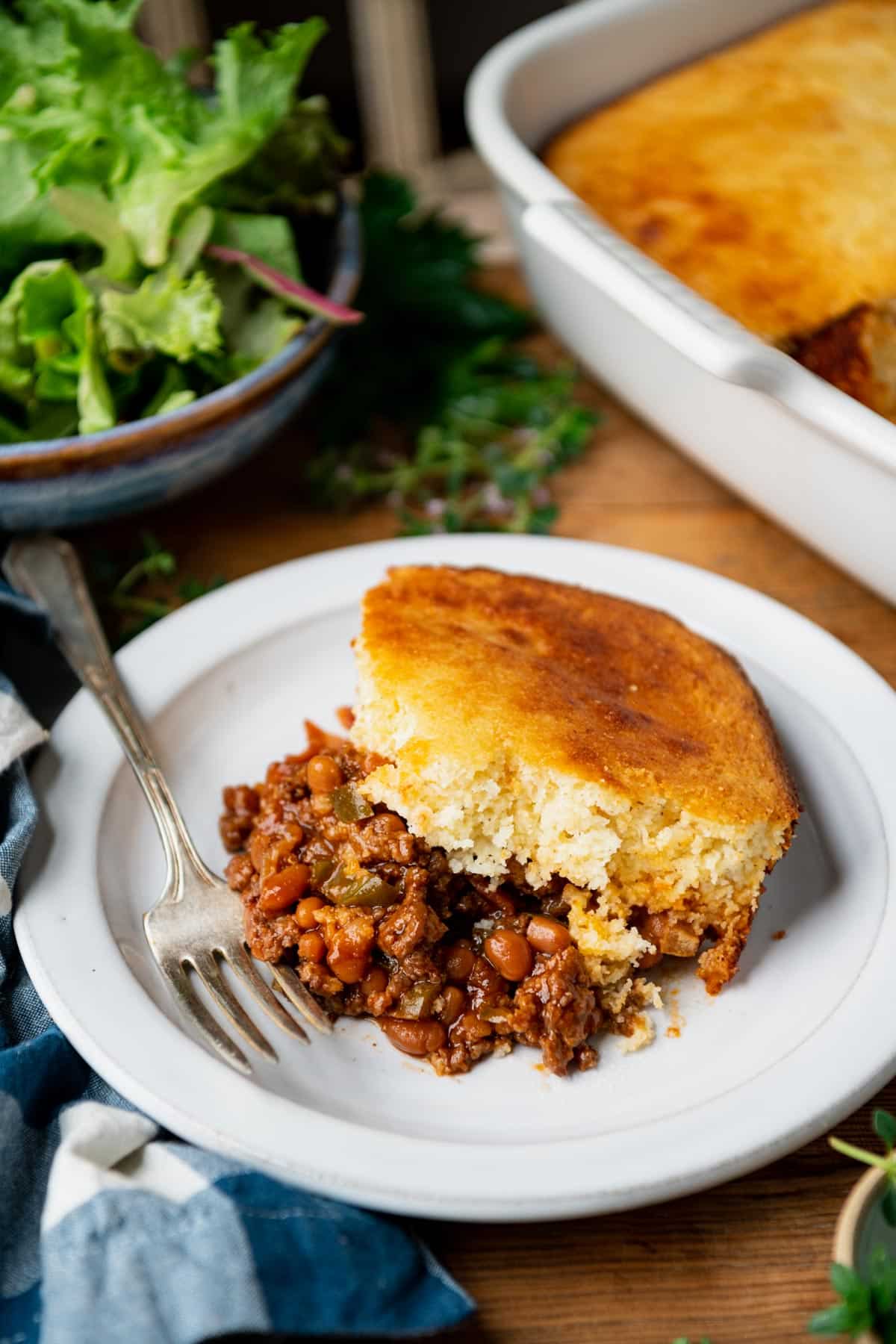 Side shot of a fork on a plate with ground beef cornbread casserole.