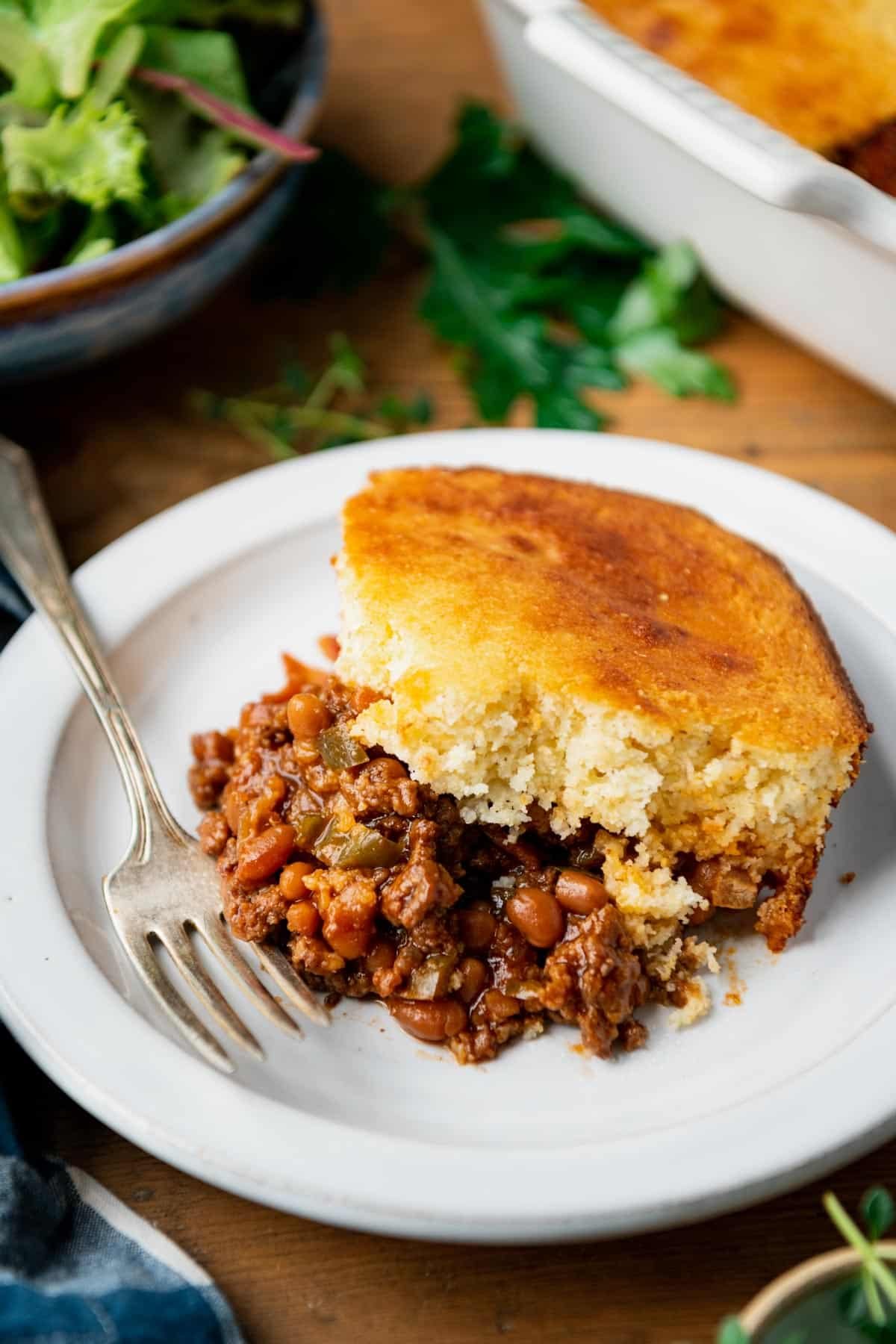 Side shot of a plate of bbq ground beef and cornbread casserole.