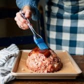 Brushing meatloaf with bbq sauce before baking.