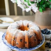 Moist blueberry pound cake on a cake stand dusted with powdered sugar.