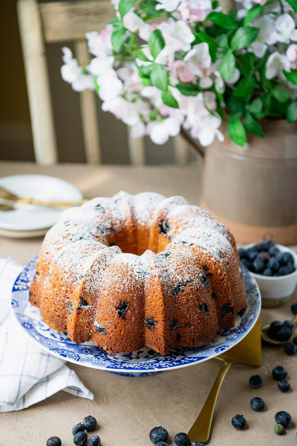 Moist blueberry pound cake on a cake stand dusted with powdered sugar.