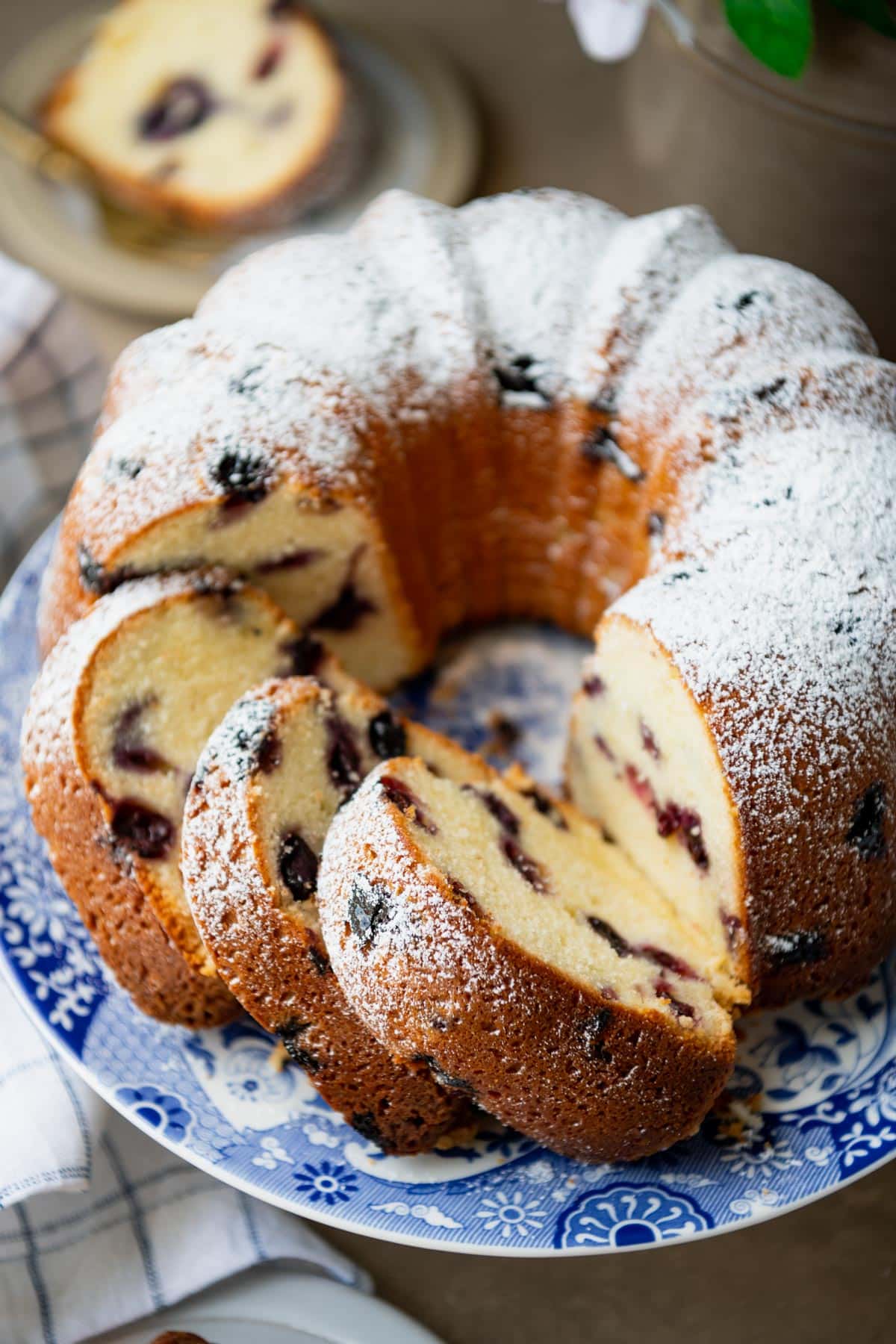 Southern blueberry pound cake sliced on a cake stand and dusted with powdered sugar.