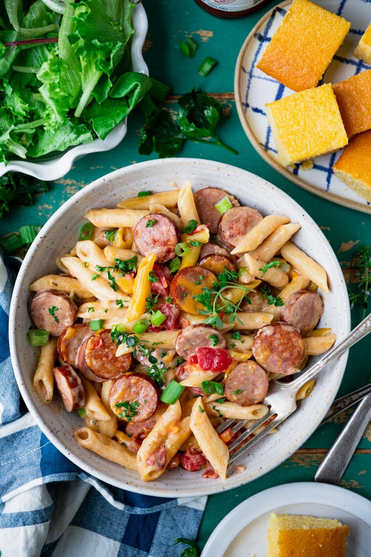 Overhead shot of a bowl of cajun sausage pasta on a turquoise table.