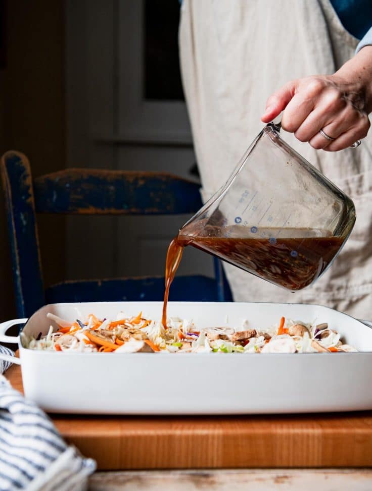 Pouring soy sauce mixture over egg roll casserole ingredients.