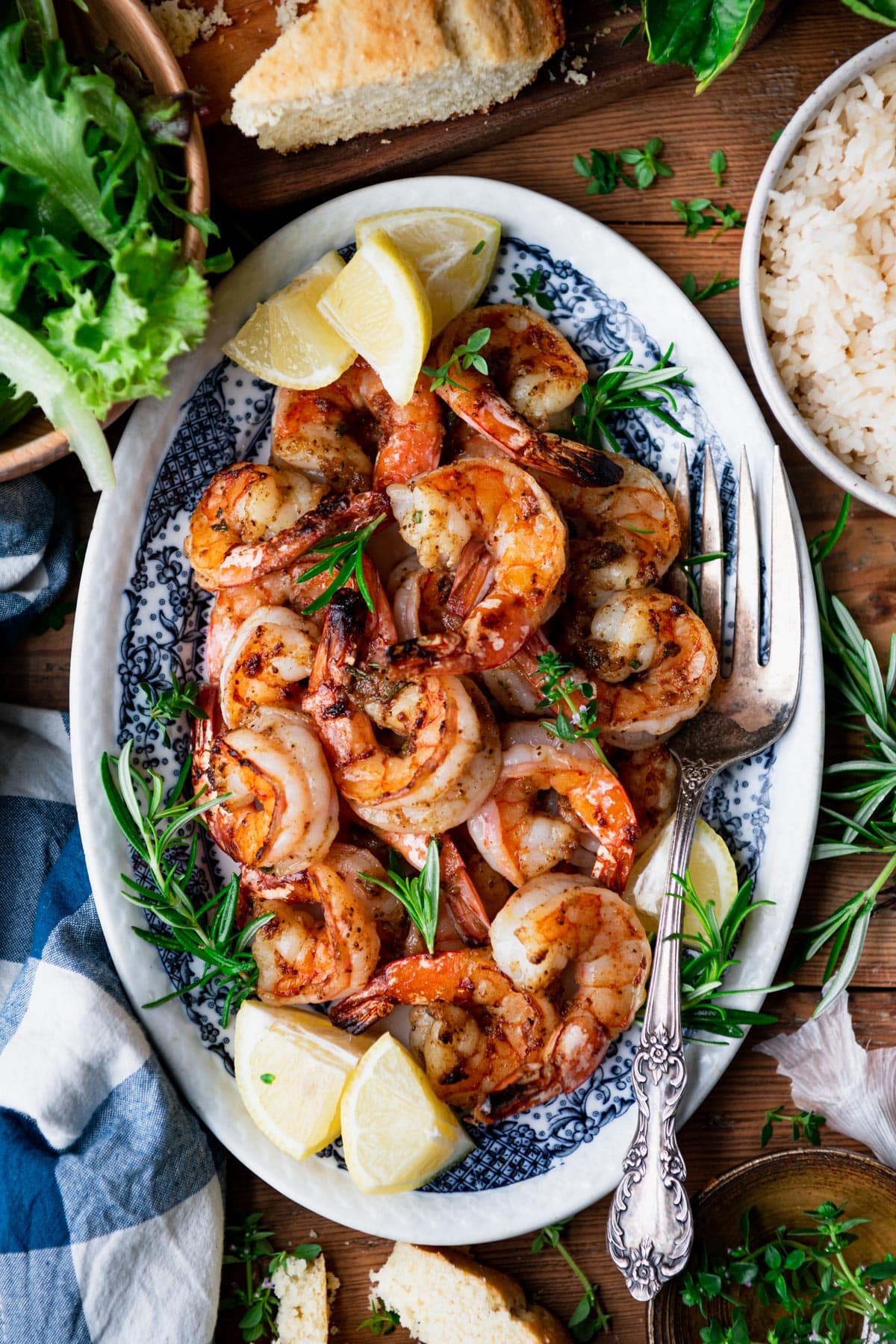 Tray of the best broiled shrimp recipe served on a wooden dinner table with a side salad and rice.