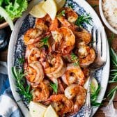 Close overhead image of a blue and white tray of garlic and rosemary broiled shrimp.