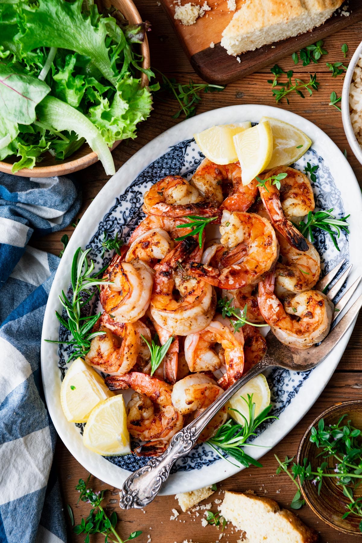 Close overhead image of a blue and white serving platter with broiled shrimp on it.