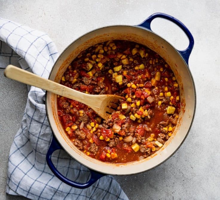 Cooking ground beef with corn and tomato sauce in a dutch oven.