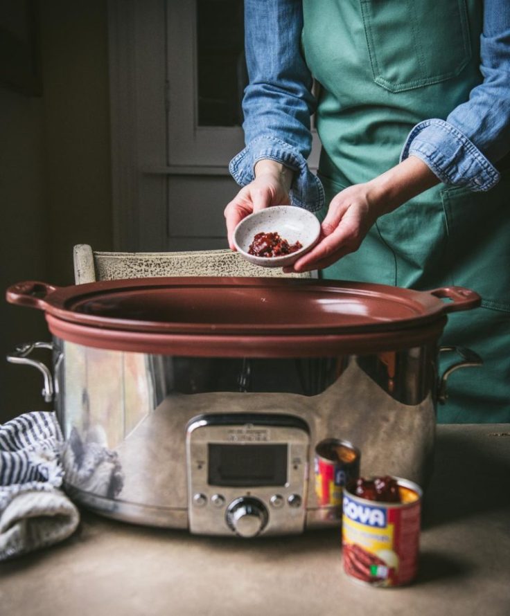 Process shot showing how to make slow cooker pulled pork tacos.