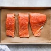 Uncooked salmon filets on a baking sheet.