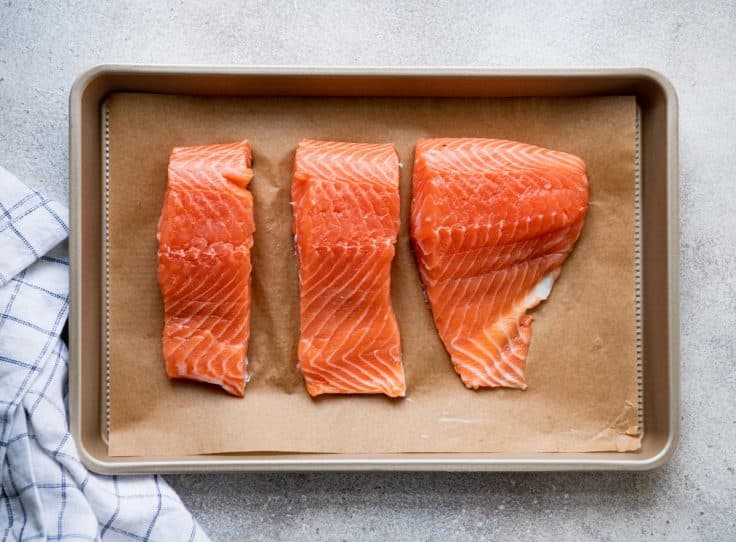 Uncooked salmon filets on a baking sheet.