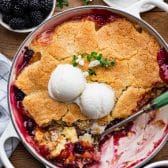 Overhead shot of peach blackberry cobbler with two scoops of vanilla ice cream.