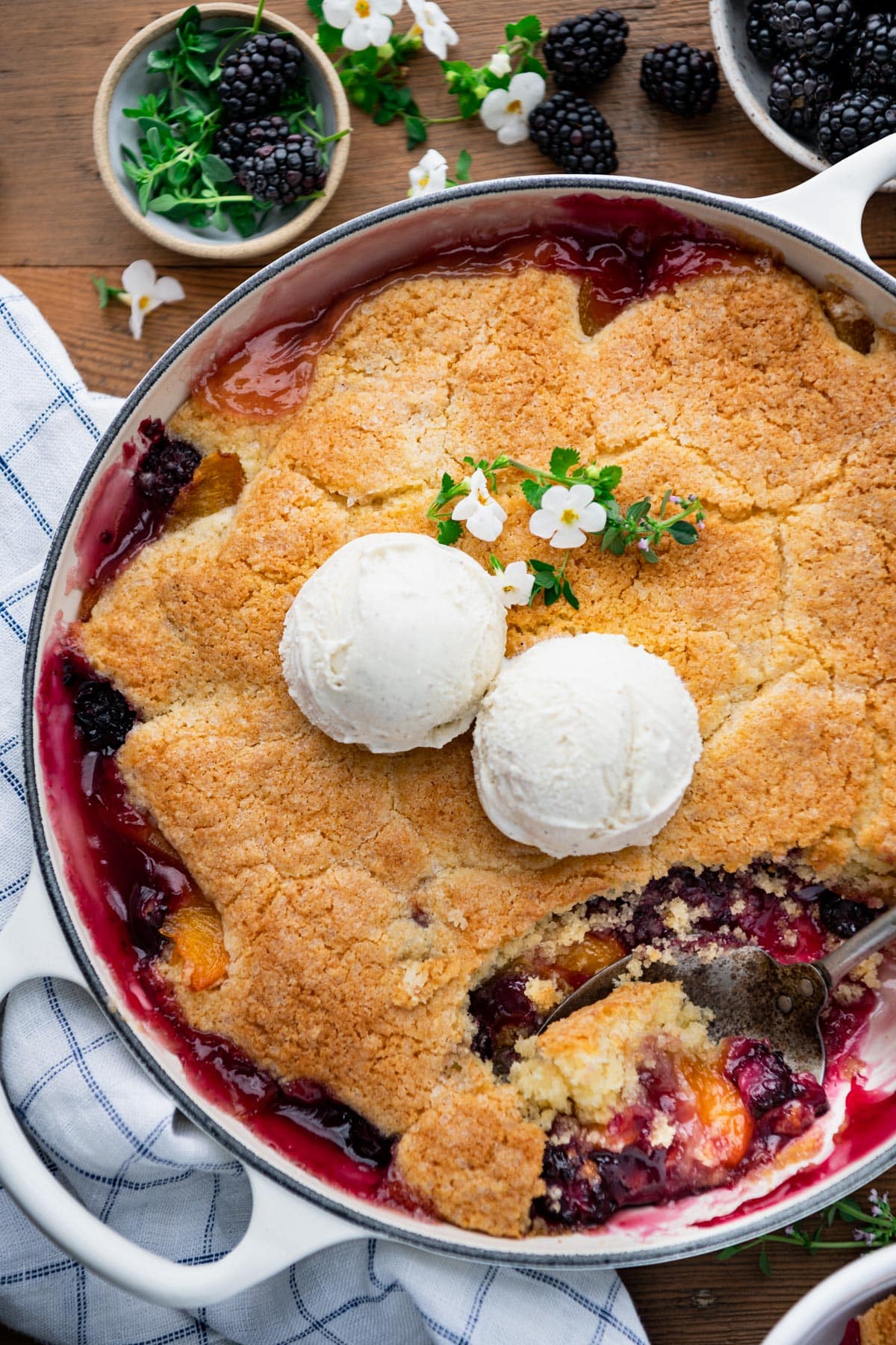 Close overhead image of blackberry and peach cobbler with ice cream on top.