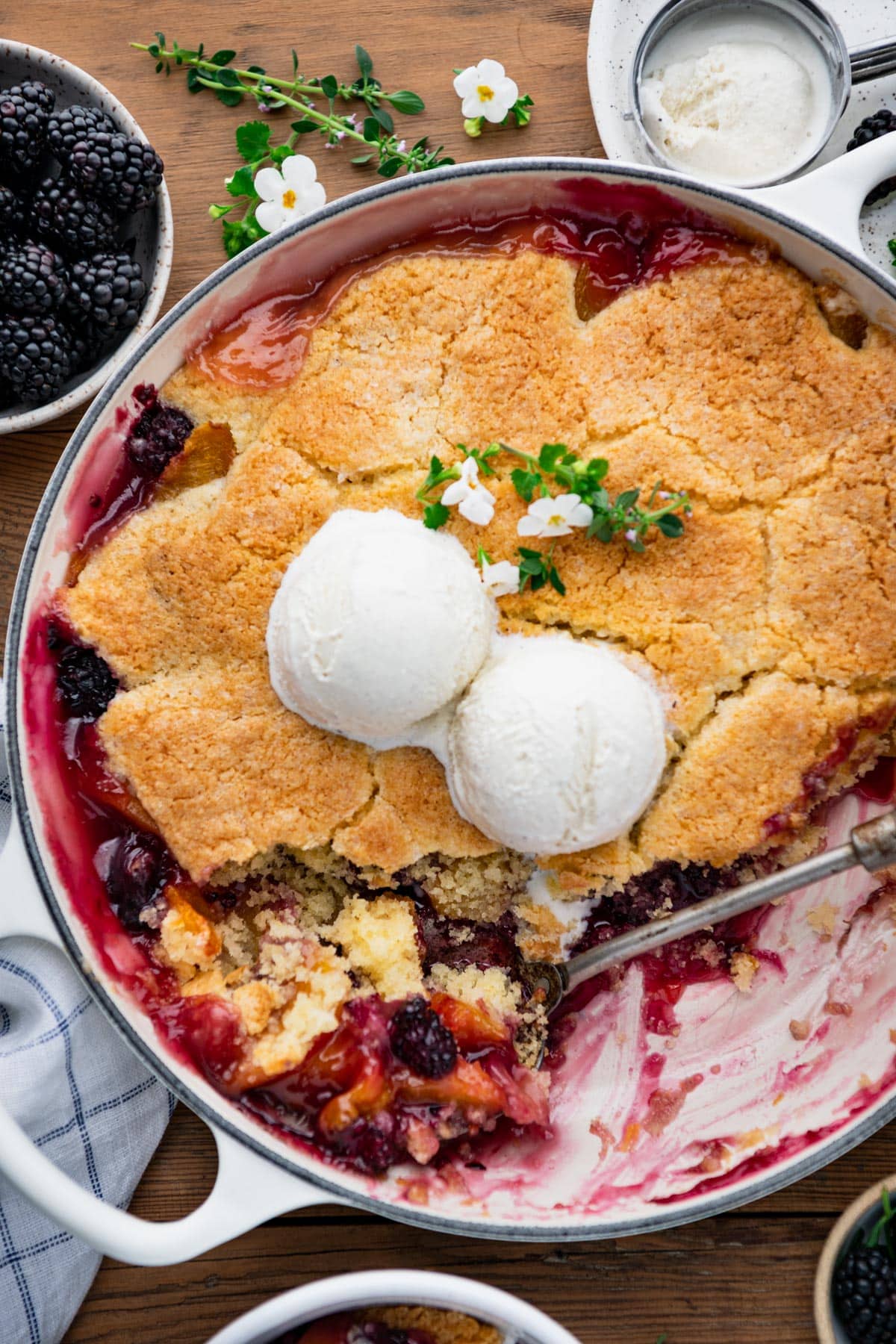 Close overhead shot of a serving spoon in a pan of peach blackberry cobbler.