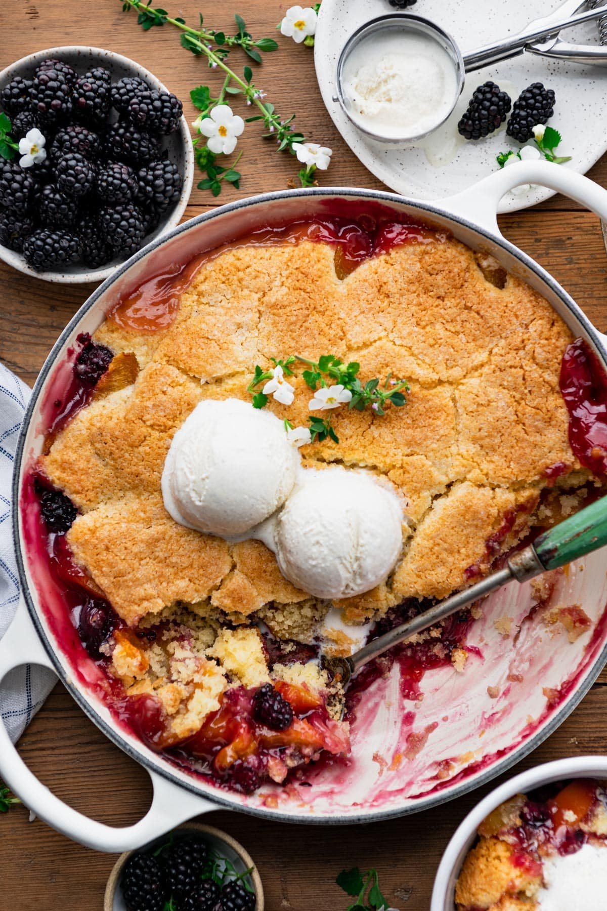 Easy blackberry peach cobbler with cornmeal biscuit crust on a wooden table.