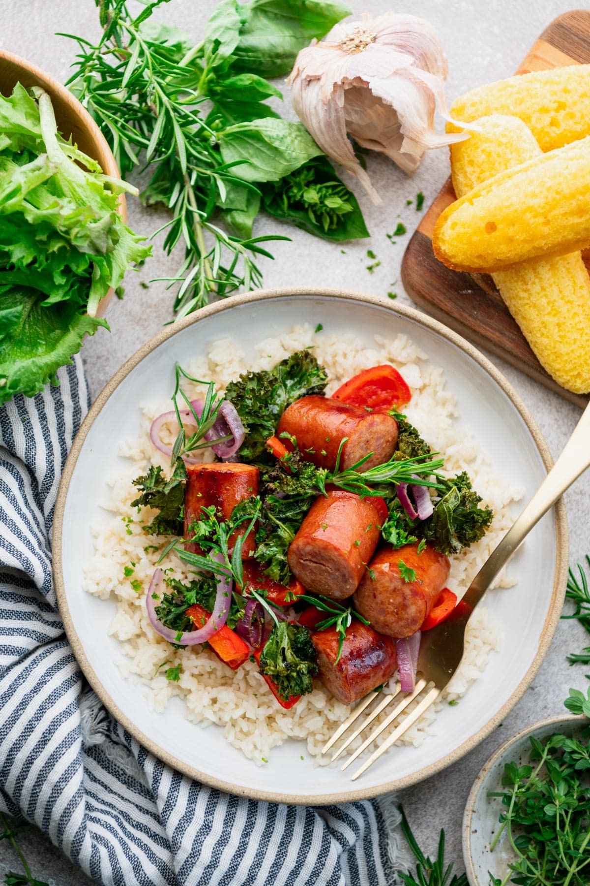 Andouille sausage recipe with peppers, onions, and greens in a bowl with a side of rice.