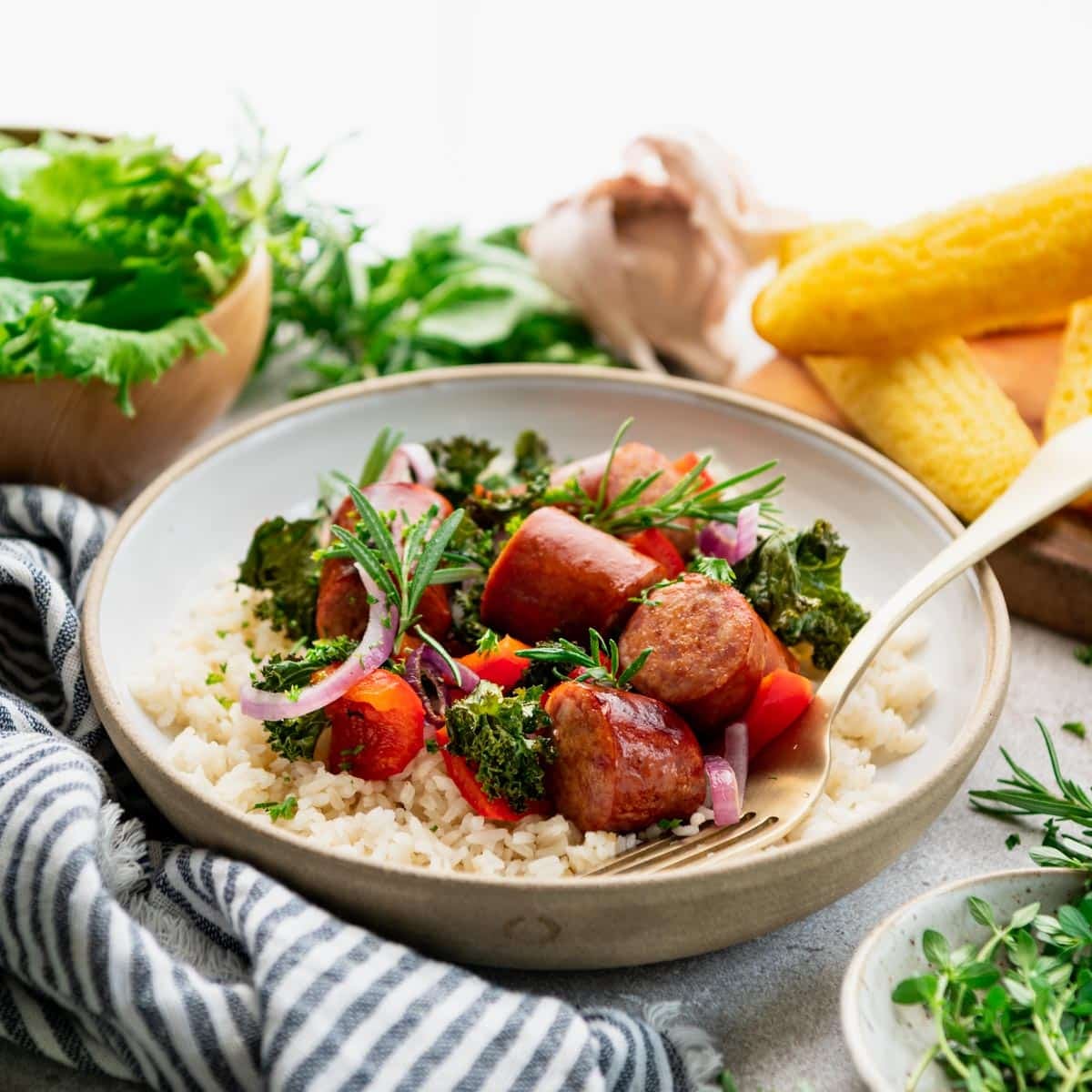 Square side shot of a bowl of andouille sausage with vegetables and rice.