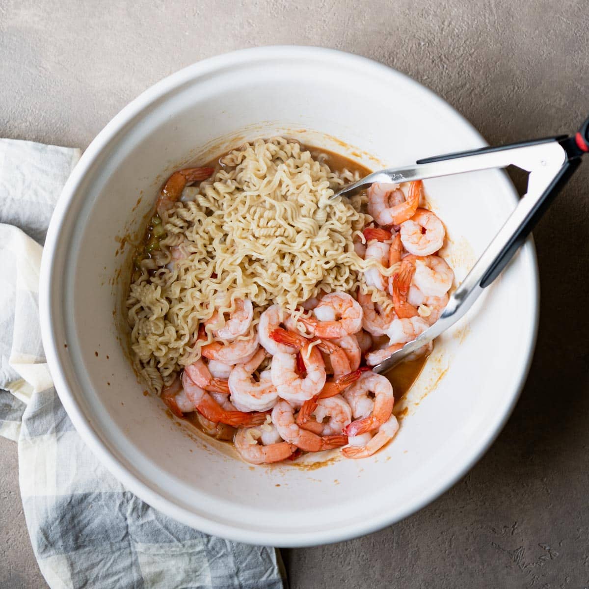 Shrimp and ramen noodles in a white mixing bowl.