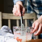Whisking egg yolk, cream, and vanilla extract in a glass measuring cup.