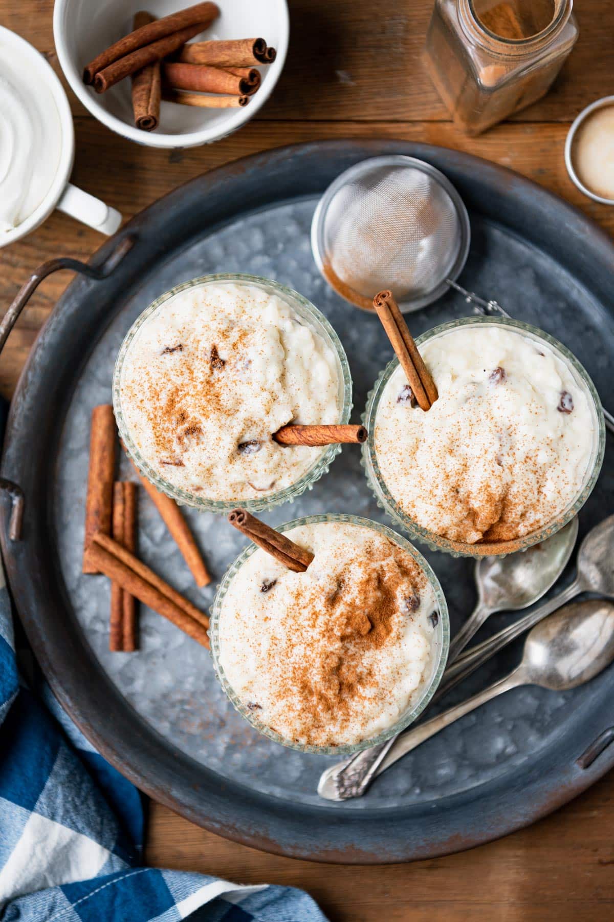 Overhead image of three bowls of southern rice pudding on a metal tray.
