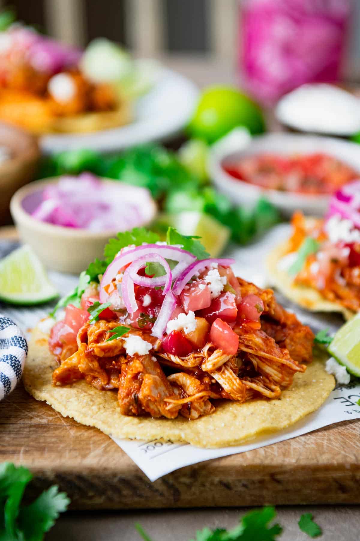 Front shot of a table of tostada de tinga with many toppings.