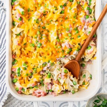 Square overhead shot of a ham and noodle casserole in a white dish.
