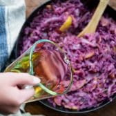 Pouring vinegar into a skillet of red cabbage.