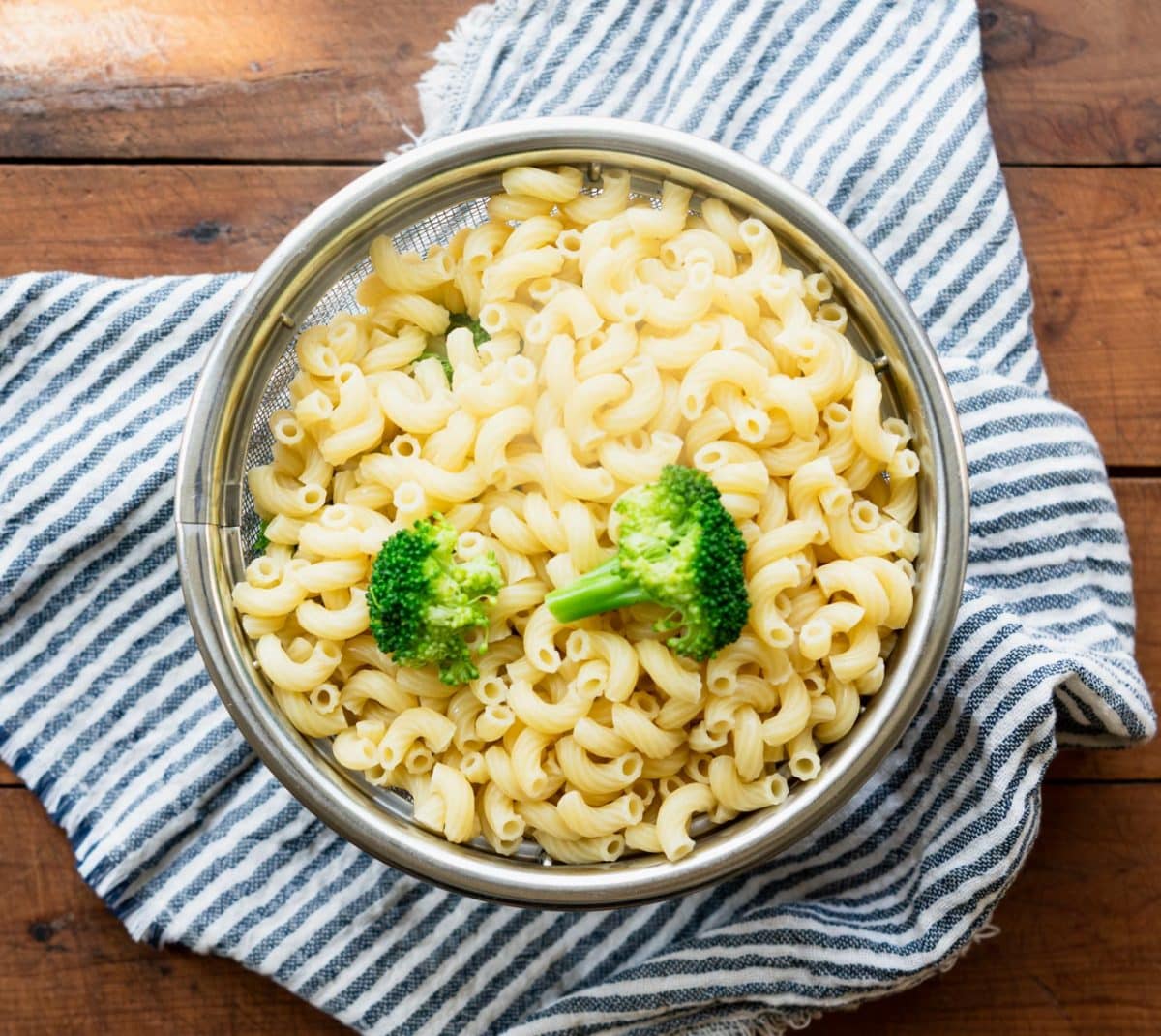 Elbow macaroni and broccoli florets in a colander.