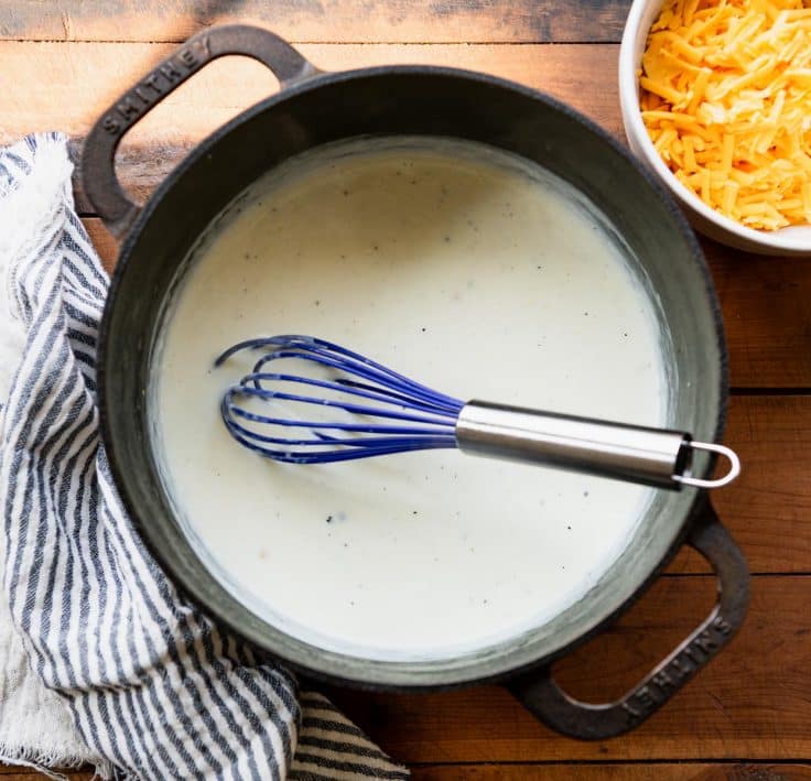 Whisking a white sauce in a Dutch oven.